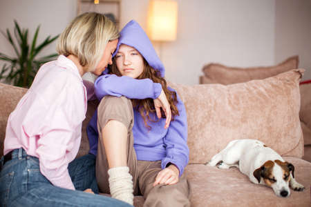 Caring mom touch comfort upset teenage daughter having difficulties with studying at home, supportive loving mother caress console sad teen child suffering from school problemsの写真素材