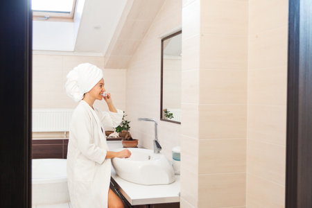 Adult woman brushing her teeth at mirror. Female in bathroom at morningの写真素材