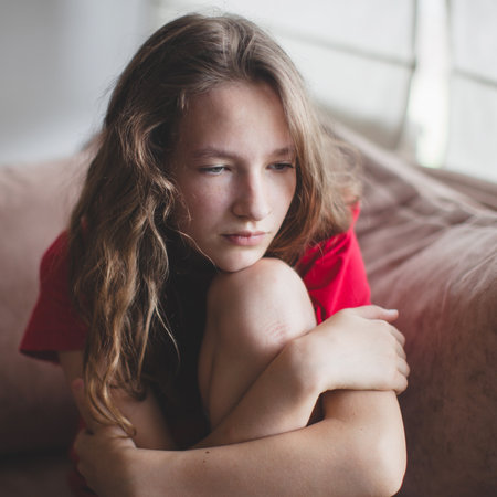 Teen girl anxious worried woman sitting on couch at home. Frustrated confused female feels unhappy, problems in personal life, quarrel break up with boyfriend and unexpected pregnancy conceptの写真素材