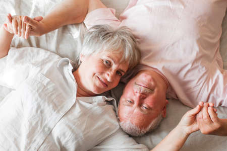 Senior couple lying in bed together. Romantic couple in love at bedroomの写真素材