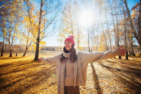Happy young woman at the autumn park. Pretty teen girl expressing freedom outdoor at fallの写真素材