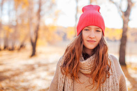 Portrait of funny young girl in the autumn weather in warm clothes and hatの写真素材