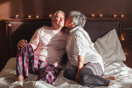Happy morning. Middle-aged couple having a romantic moment in the bedroom. Older couple in bed at homeの写真素材
