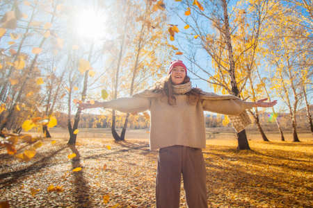 Young happy Woman with scarf and cap. Attractive teen girl wearing woolen clothes for autumnal season with outstretched armsの写真素材