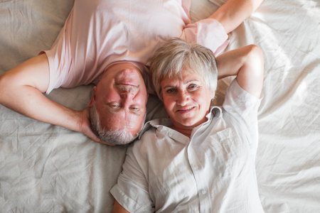 Senior couple lying in bed together. Romantic couple in love at bedroom. top viewの写真素材