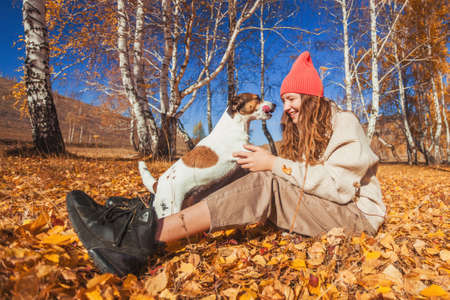 Young happy Woman with scarf and cap. Attractive teen girl wearing woolen clothes for autumnal season with dogの写真素材