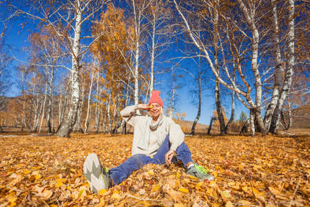 Portrait of funny middle aged woman in the autumn weather in warm clothes and hats. Happy mature lady walks in the park, enjoys the yellow autumn leaves in fallの写真素材