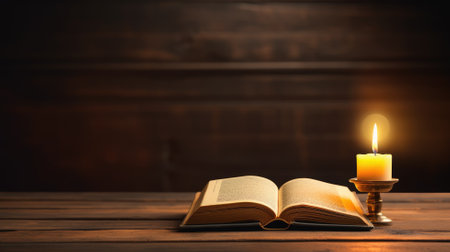 An open book beside a burning candle on a wooden table, evoking a sense of study and relaxationの素材