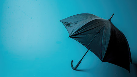 Black umbrella with raindrops against a blue backgroundの素材