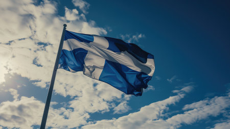 A historical Icelandic flag, HvÃ­tblÃ¡inn flutters against a blue sky with cloudsの素材