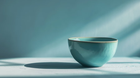 Turquoise ceramic bowl on a blue shadowed surfaceの素材