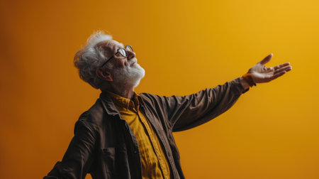 Elderly man with glasses reaching out on a yellow backgroundの素材