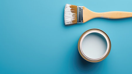 A fresh paintbrush beside an open can of white paintの素材