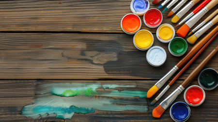 A vibrant collection of paint pots and brushes on a rustic wood surface, showcasing a palette of creativityの素材