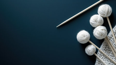 White knitting yarn balls with needles on a dark contrasting backgroundの素材