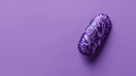 A single fingernail painted in intricate purple patterns, showcased against a complementary purple backdrop, demonstrating precision in nail artistryの素材