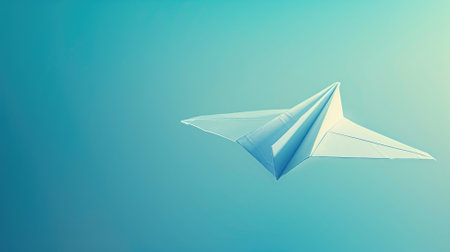 White paper airplane against blue background mid-flightの素材