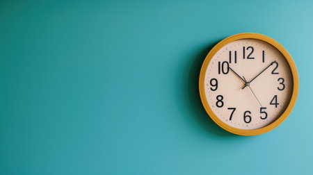 Simple wall clock displaying time 10:10 against solid teal backgroundの素材