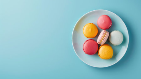Colorful macarons arranged on white plate against blue backgroundの素材