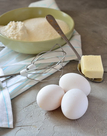 Ingredients for cake - eggs, flour, sugar, butter, whisk
