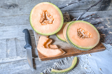 Slices of ripe melon on a chopping board with a knife and napkinsの写真素材
