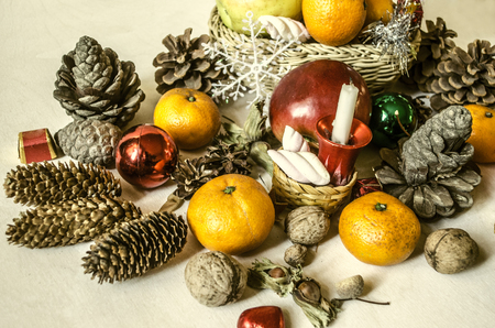 Mandarins,nuts,snowflakes,balls,straw baskets with fruits and sweets on light wooden tableの写真素材