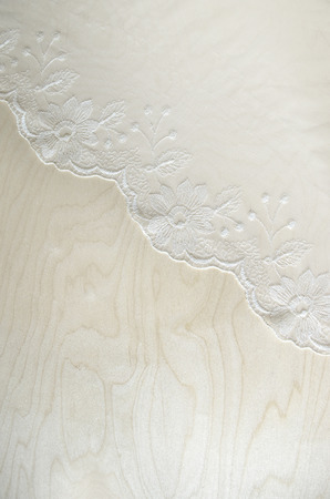 Ancient embroidered laceÂ with flowers lay at an angle on light plywoodの写真素材