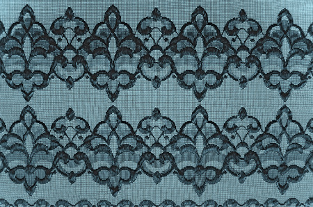 Black ornament on a fine mesh fabric stretched over a blue backgroundの写真素材