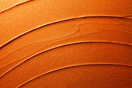 Glossy golden orange lipstick background texture smudged