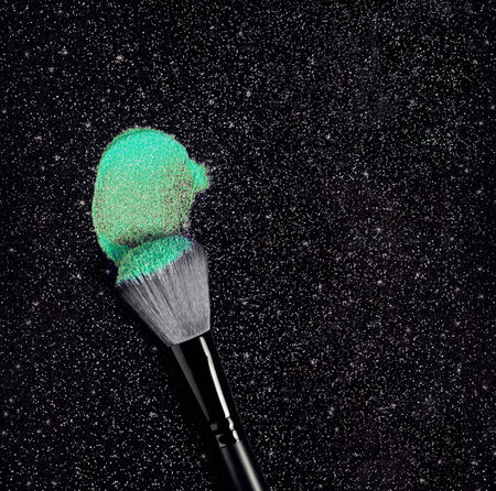 Shimmering glow emerald green eye shadow cosmetic powder smudge brush stroke on blackの写真素材