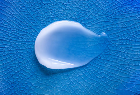 White cream smudge swatch textured cyan blue colored cracked backgroundの写真素材