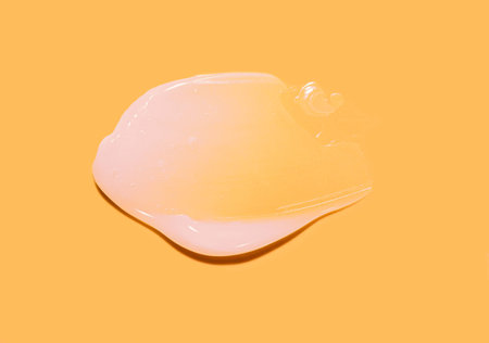White moisturizing cream gel smudge swatch textured yellow orange colored background. Hair or skin...