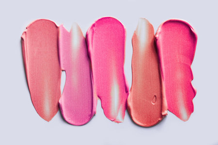 Lip gloss palette assortment swatches pink rose peach coral orange on gray backgroundの写真素材