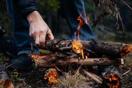 A man tries to light a fire and throws dry straw into the fireの写真素材