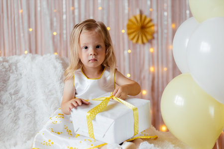 A little girl is unwrapping her birthday giftの写真素材