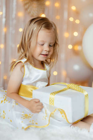 A little girl is unwrapping her birthday giftの写真素材