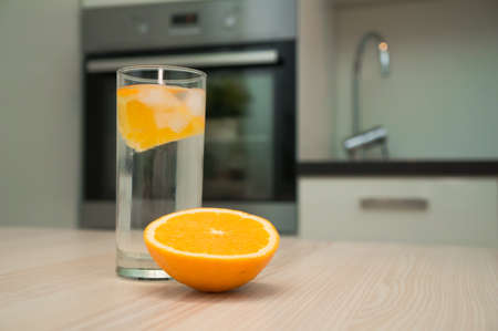 Glass of water with orange on the kitchen tableの写真素材