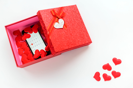 Smartphone with calendar at 14 february date and hearts in opened red gift box. Present and gift ar Valentine's day White background.の写真素材