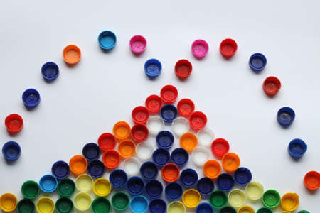 Volcano with lava, magma made of plastic colorsful bottle tops, caps on white background.の写真素材
