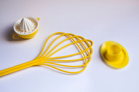 Retro almost flat lay background with lemon squeezer, egg cup, and plastic carpet tool on white...