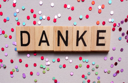 Thank you card with german language DANKE on wooden block on lila background with shiny glitters,...