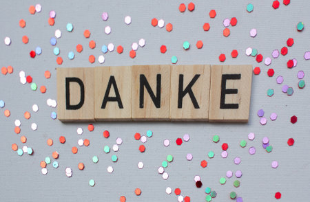 Thank you card with german language DANKE on wooden block on background with shiny glitters, panoramaの写真素材