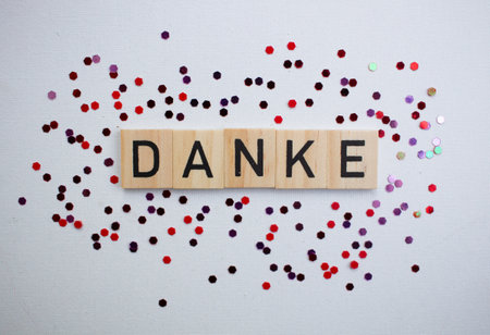 Thank you card with german language DANKE on wooden block on background with shiny glitters, panoramaの写真素材