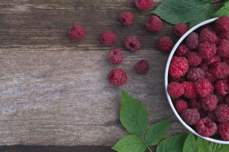 Raspberries in a bowl on a wooden table.