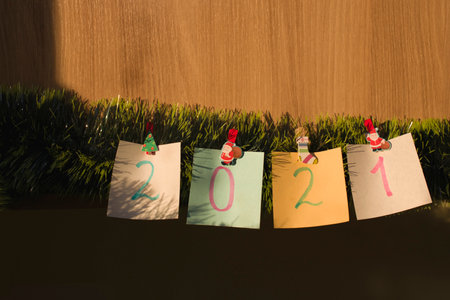 Colored sticky notes with the year number 2021, attached to it with New Year's clothespins to an...