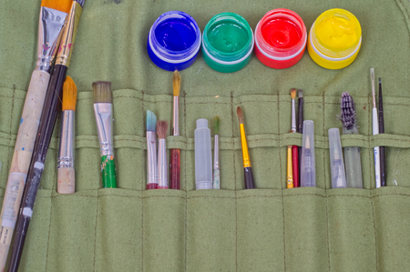 Artistic brushes and paint bottles in a special case for keeping artistic equipment.の写真素材