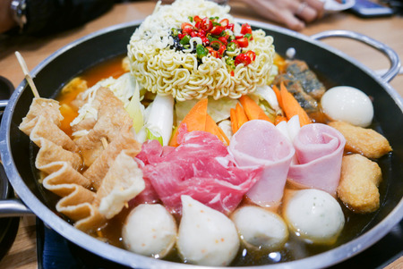 Korean Hot pot 'Budae Jjigae' or Army Stew is Korean fusion food incorporates American style with noodle, ham, sausages, canned baked beans, sliced cheese and Kimchi.の写真素材