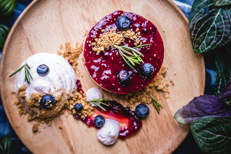 Delicious homemade cheesecake with berry sauce set on wooden plate.の写真素材