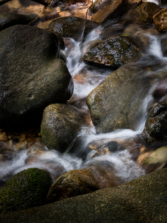 mountain stream creek waterfall flowing through rocks.の写真素材