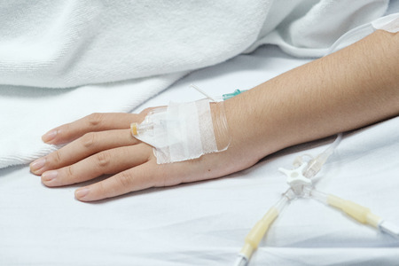 Hospital patient hand with saline solution in Intravenous Drip Dropper in hospital.